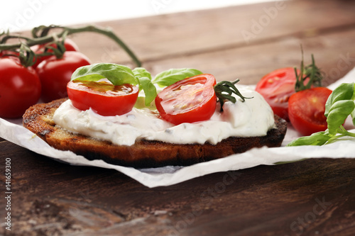 Bread with cream cheese and tomato for lunch table. Sharing antipasti on party or summer picnic time over wooden rustic background.