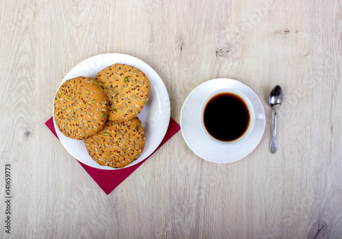 A cup of coffee and biscuits. On a wooden background.