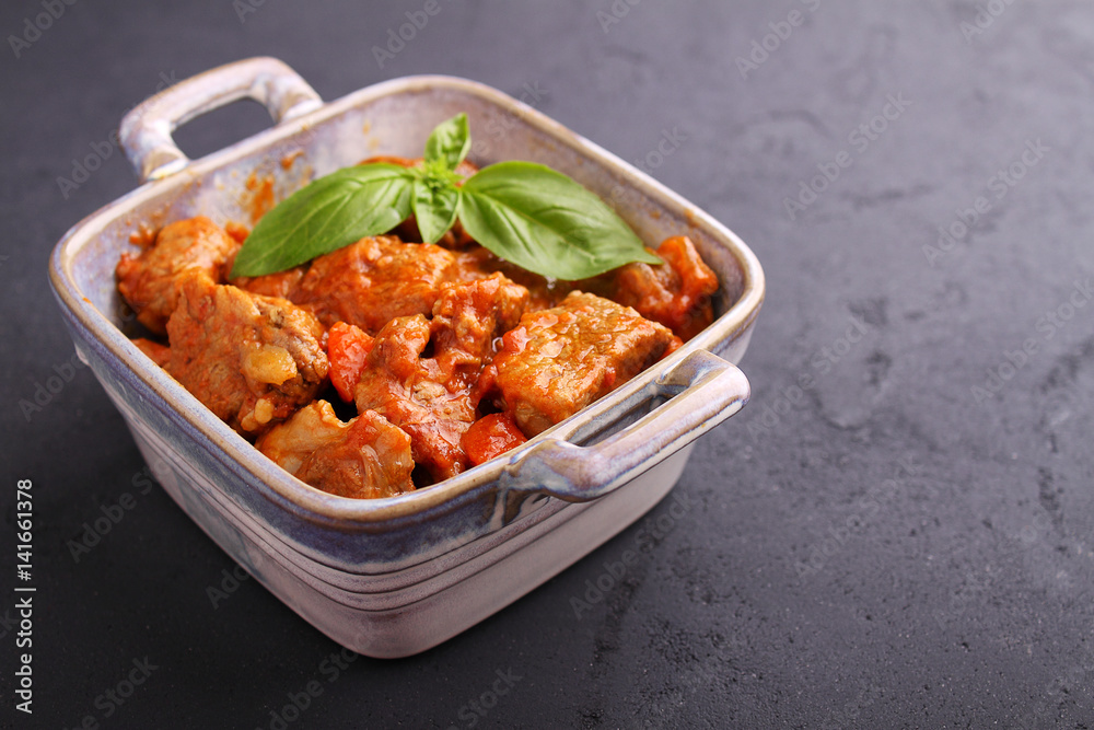 Ragout of meat with onions, carrots and tomatoes, decorated with basil,