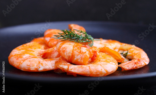 shrimp and dill in black plate on a black background