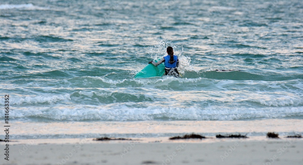 Une jeune femme s'avance dans la mer pour pratiquer le surf