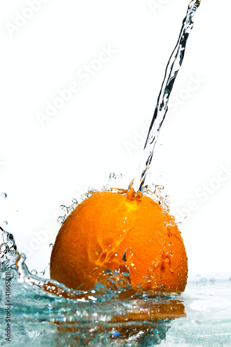 Orange in streams of water on a white background, studio light