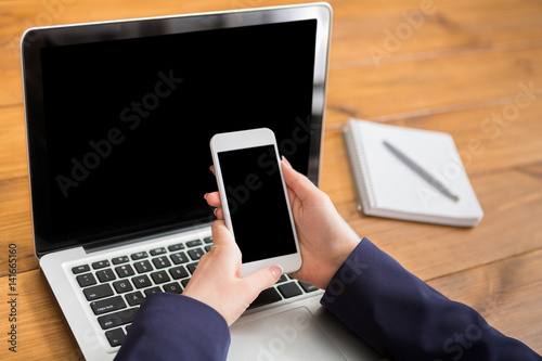 Close-up of woman using laptop and smartphone