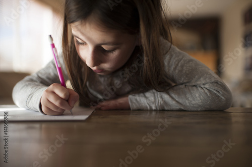 Girl writing homework at home photo