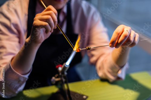 Lampworking - artistic treatment of glass in the flame. Woman master work gas. Burner glows (focus on the tools).