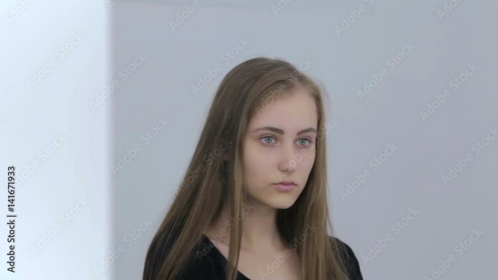 Pretty, young and sensual teen girl with long hair without make-up looking at her reflection in mirror. Natural beauty concept