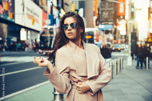 Fashionable girl walking on New York City street in Midtown wearing sunglasses and ping jacket. © Nick Starichenko