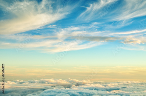 Abstract background with gold and blue colors clouds. Sunset sky above the clouds. Dreamy fantasy background in soft pastel colors .