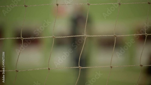 Close Up Of Volleyball Net While Players Play And Cheer In The Background photo