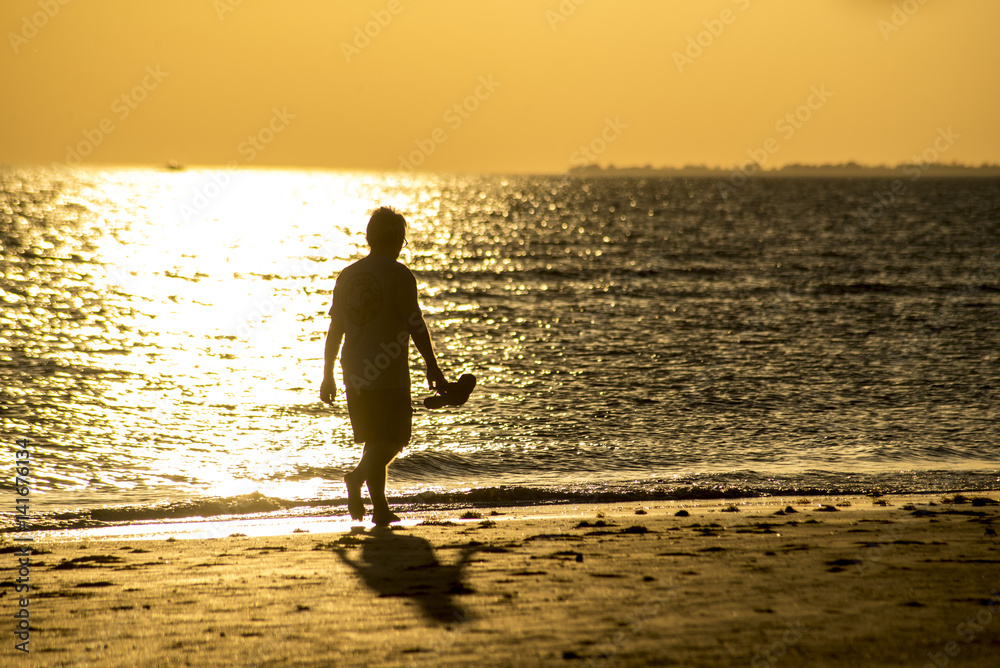 Man's silhouette on the beach at sunset.