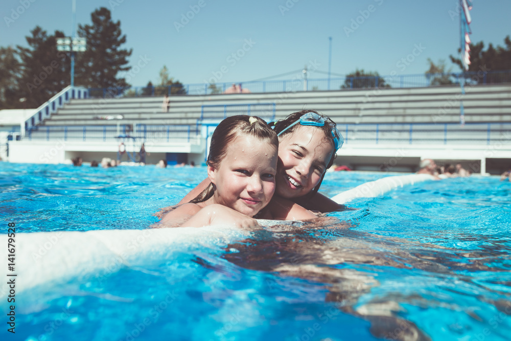 Underwater fun. Two cute little girls with goggles swimming underwater and diving in the swimming poll. Kids sport and leisure.