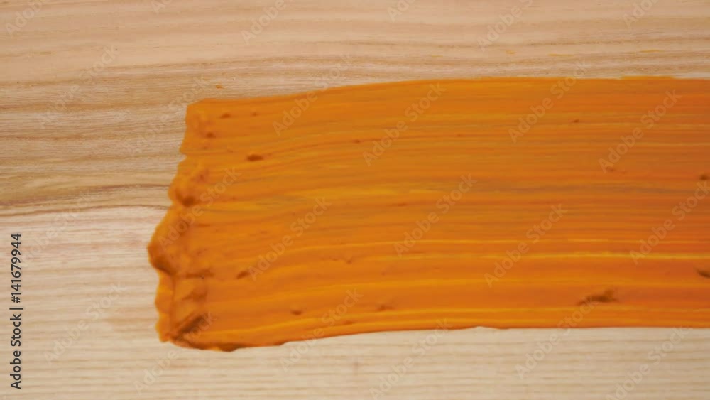 A painter painting with brush a wooden doard. Orange paint macro A painter painting with brush a wooden doard. Orange paint macro