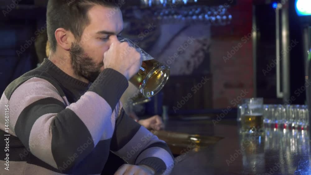 Attractive bearded guy smelling beer at the pub. Side view of handsome male customer taking a sip of lager at the bar counter. Brunette caucasian man smiling for the bartender Attractive bearded guy smelling beer at the pub. Side view of handsome male customer taking a sip of lager at the bar counter. Brunette caucasian man smiling for the bartender