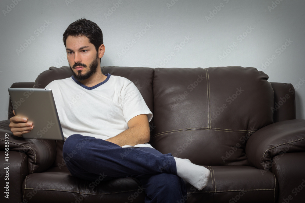 Portrait of a man using tablet and sitting on couch. Indoors
