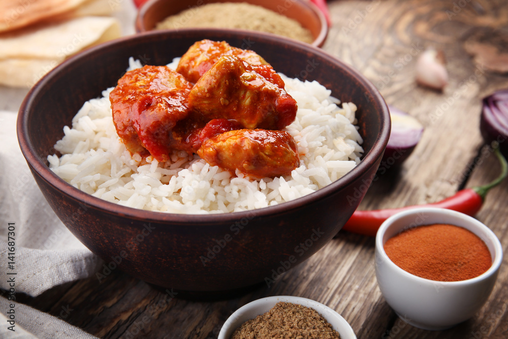 Bowl with delicious chicken tikka masala, rice and spices on table Bowl with delicious chicken tikka masala, rice and spices on table
