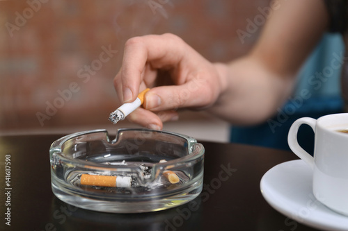 Smoking woman s hand holding cigarette sitting at table