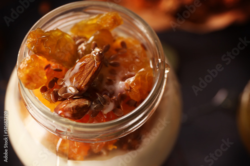 Delicious yogurt with almond and raisins in glass jar, closeup
