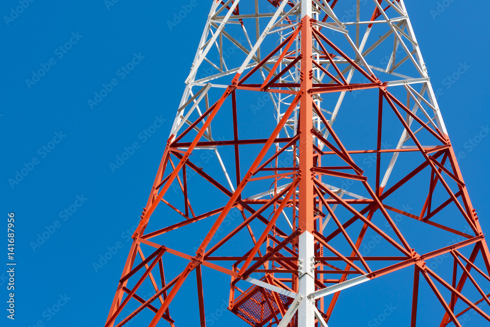 Mobile phone communication antenna tower with satellite dish on blue sky background