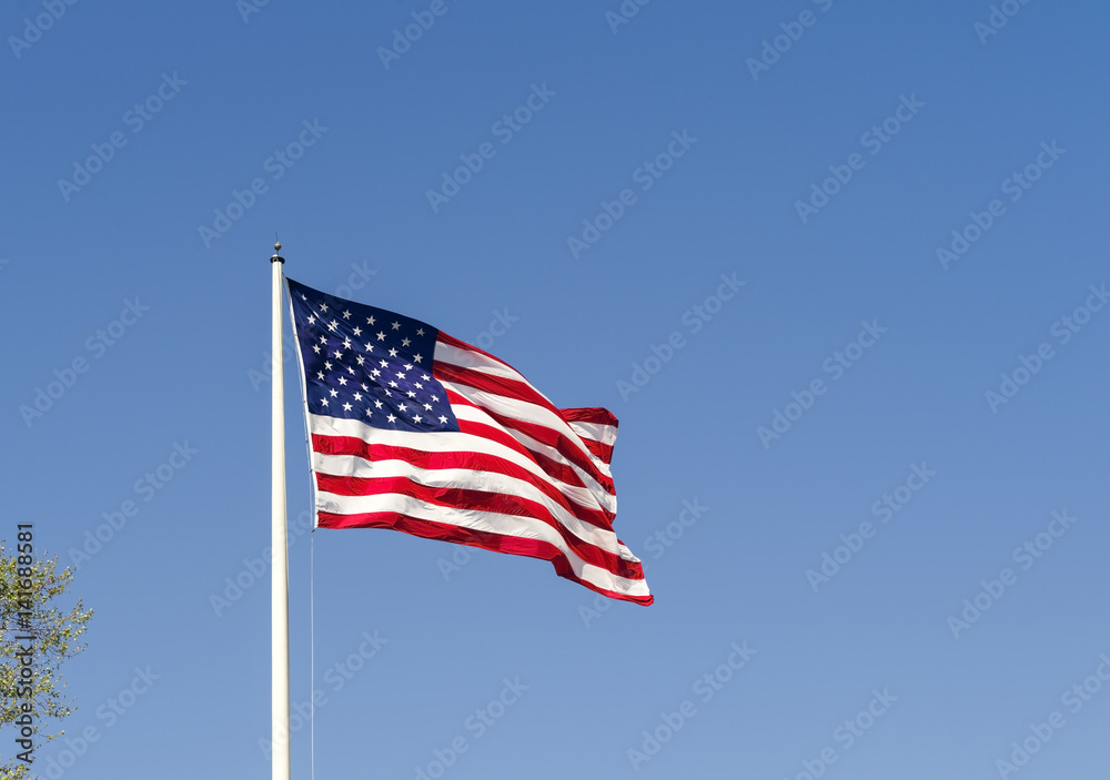 An American flag waving against a blue sky.