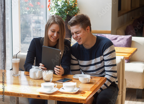 Cheerful couple dating in a cafe. They are having fun and smiling with tablet.  Dating, love, romanic, dating, lifestyle, study, education. Natural emotion