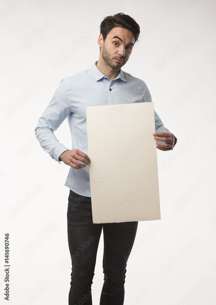 Young happy man showing presentation, pointing on placard over gray background Young happy man showing presentation, pointing on placard over gray background