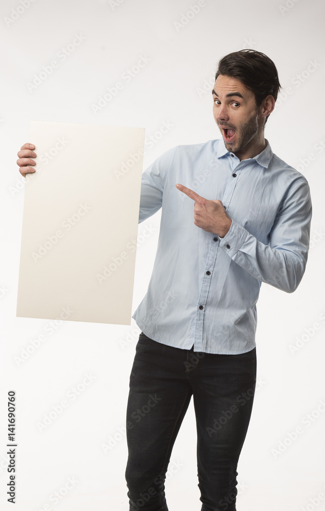 Young happy man showing presentation, pointing on placard over gray background Young happy man showing presentation, pointing on placard over gray background