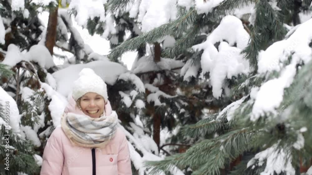 Beautiful young woman bobbing and throwing snow off tree branches, laughing and having fun in the winter forest. Beautiful young woman bobbing and throwing snow off tree branches, laughing and having fun in the winter forest.
