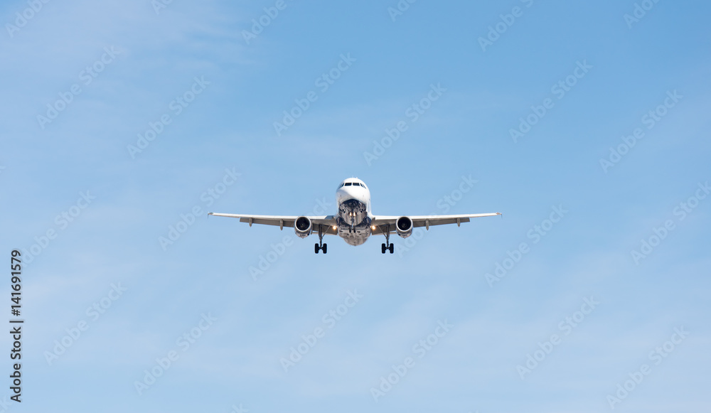 Commercial airplane flying in blue sky, full flap and landing gear extended