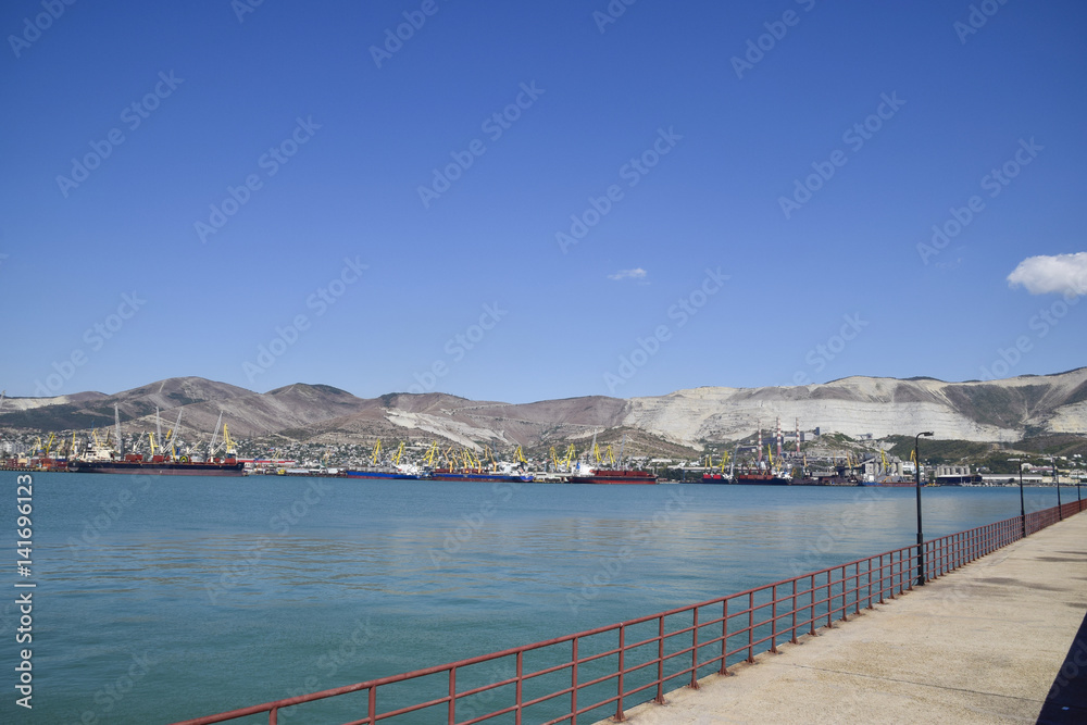 Cargo port with port cranes. Sea bay and mountainous coast. Cargo port with port cranes. Sea bay and mountainous coast.