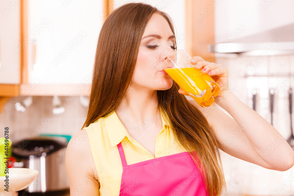 Woman in kitchen drinking fresh orange juice Woman in kitchen drinking fresh orange juice