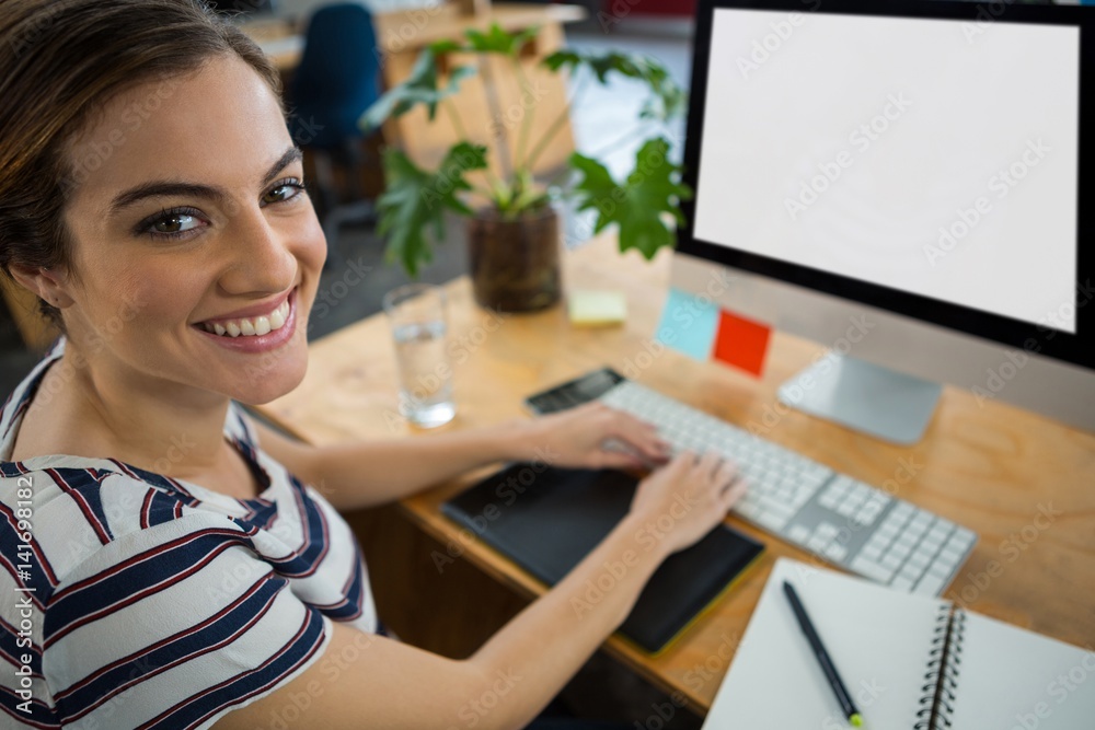 Naklejka premium Smiling female graphic designer working on computer