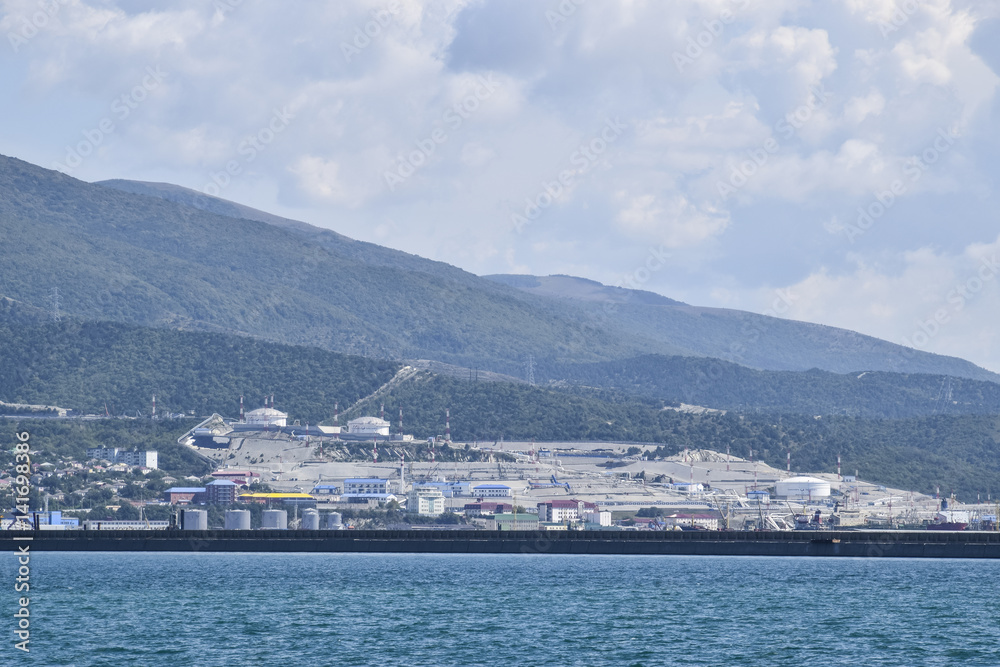 Cargo port with port cranes. Sea bay and mountainous coast.
