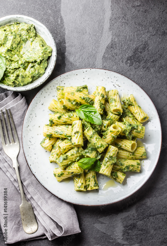 Vegetarian pasta with green avocado and herbs sauce pesto. Top view