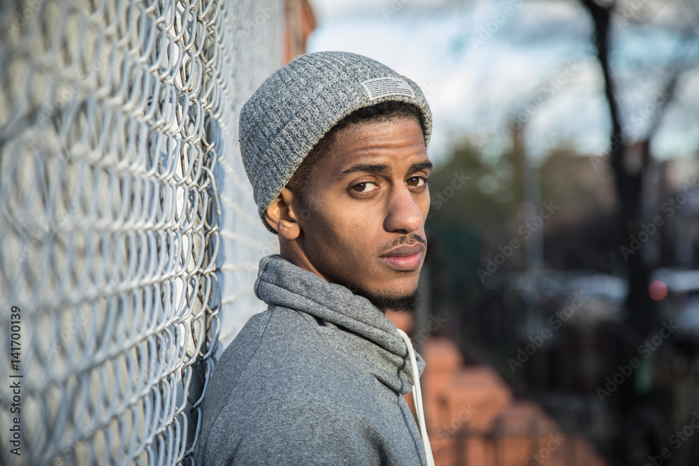 Ταπετσαρία A young, hip man poses for a pensive portrait along a fence in NYC