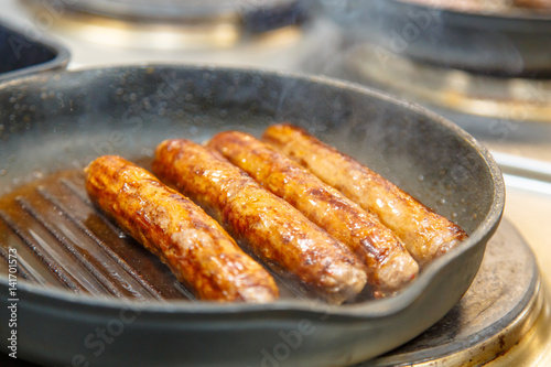 Sausage of beef fried in a skillet-grill.