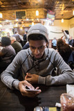 A young man texts while he waits for his food at a local diner