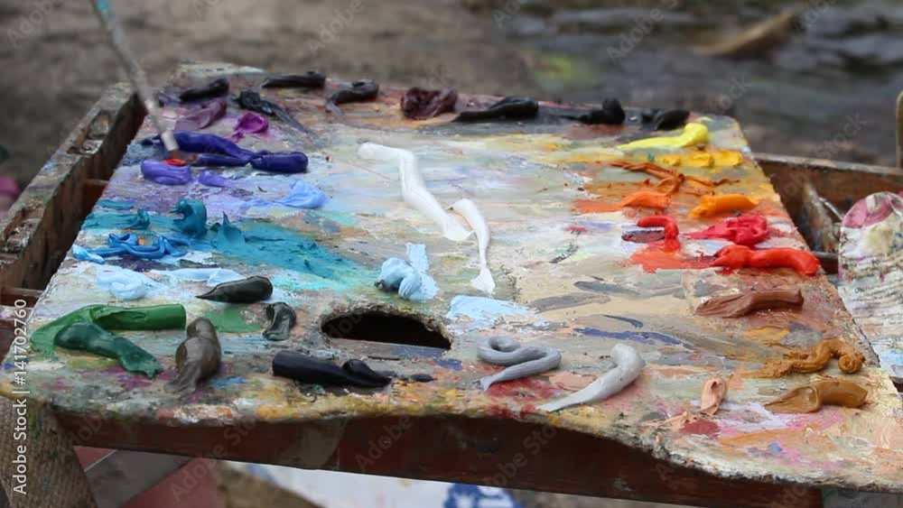 An Artist's Palette With Oil Paint. A painter arranges and mixes paints. En plein air painters painting An Artist's Palette With Oil Paint. A painter arranges and mixes paints. En plein air painters painting