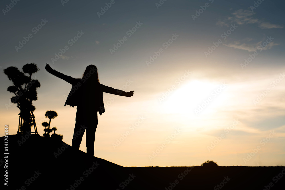 woman silhouette standing raise hand on sunset