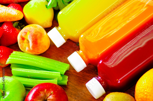 Bottles of delicious organic juice lying on desk sorrounded by fruits and veggies, beautiful colors, healthy lifestyle concept photo