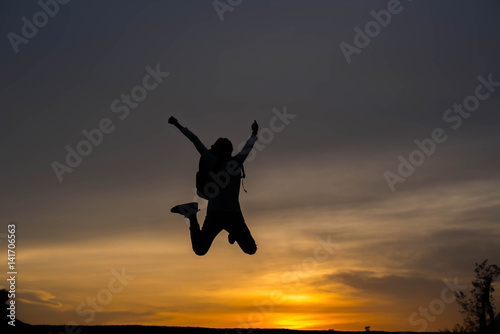 Silhouette woman jumping at sunset