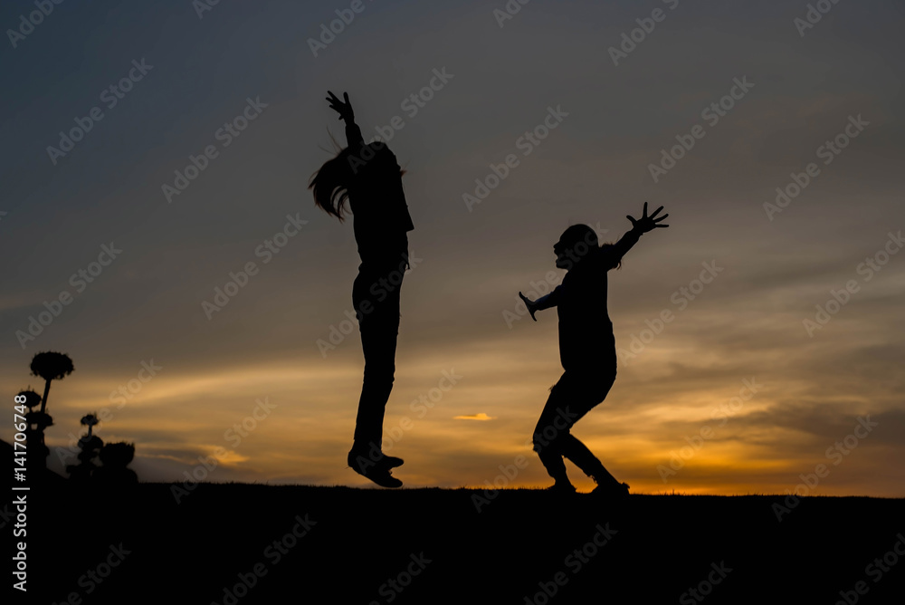 Silhouette woman jumping at sunset