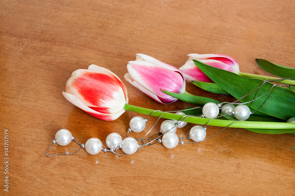 Tulips and white pearls lie on the table Tulips and white pearls lie on the table