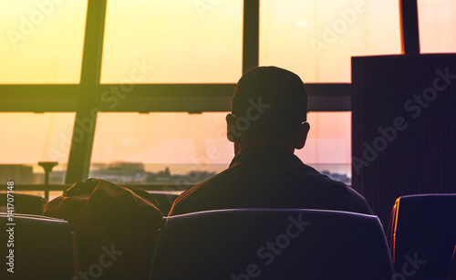 A man waring cap sitting and waiting for the flight in the airport, ready for departure,