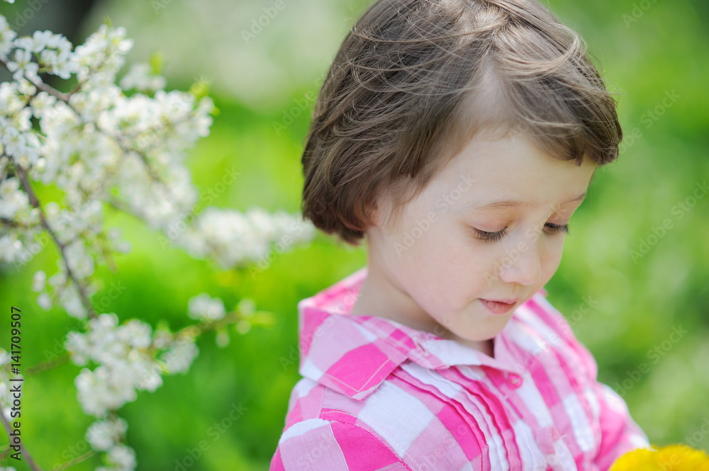 Cute little girl having fun in blooming cherry garden on beautiful spring day Cute little girl having fun in blooming cherry garden on beautiful spring day