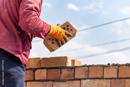 Fotografie Worker builds a brick wall in the house