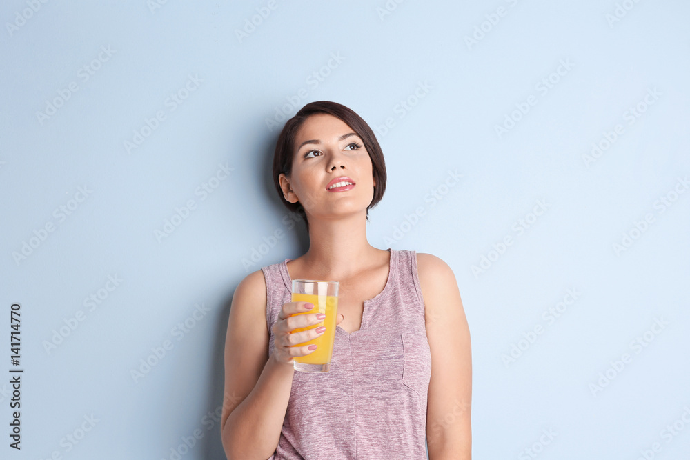 Young beautiful woman with glass of orange juice, on light background Young beautiful woman with glass of orange juice, on light background