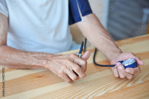 Senior man measuring pressure on wooden table