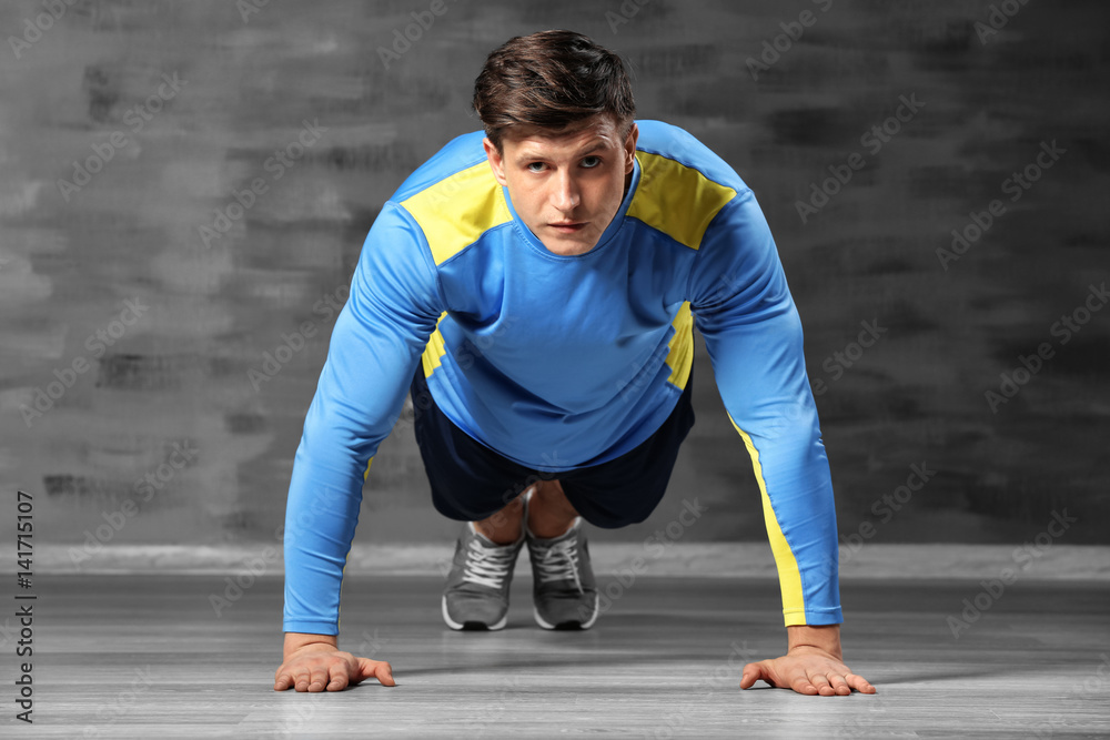 Fototapeta premium Young handsome sportsman doing exercises on color background