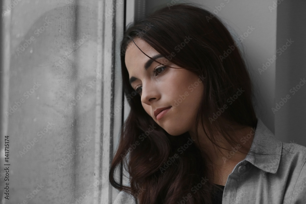 Depressed young woman near window at home, closeup Depressed young woman near window at home, closeup