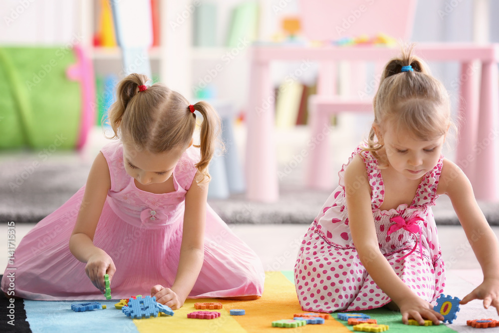 Fototapeta premium Adorable little sisters playing on floor at home